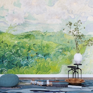 Puede incluir: Un mural de pared con una pintura de paisaje verde con pinceladas arremolinadas, un jarr&oacute;n blanco con ramas verdes sobre un soporte de metal negro, un puf de punto verde azulado y una alfombra azul con un tren de juguete y un cuenco de madera.