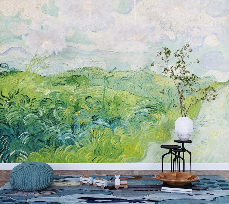 Puede incluir: Un mural de pared con una pintura de paisaje verde con pinceladas arremolinadas, un jarr&oacute;n blanco con ramas verdes sobre un soporte de metal negro, un puf de punto verde azulado y una alfombra azul con un tren de juguete y un cuenco de madera.
