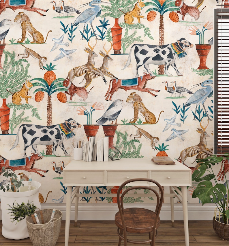 May include: A light-colored desk with three drawers and a wooden chair sits against a wall covered in wallpaper featuring a repeating pattern of various animals, including cows, deer, monkeys, and birds, alongside potted plants and palm trees.