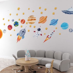 May include: A set of colorful space-themed wall decals featuring planets, stars, a rocket, an astronaut, and a UFO. The decals are perfect for a child's bedroom or playroom.