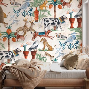 May include: A wall mural featuring a repeating pattern of ancient-style illustrations including spotted cows, deer, birds, monkeys, and palm trees with orange fruit on a cream background, positioned behind a bed with striped bedding and pillows.