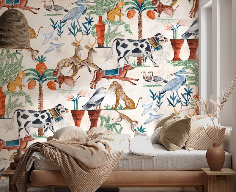 May include: A wall mural featuring a repeating pattern of ancient-style illustrations including spotted cows, deer, birds, monkeys, and palm trees with orange fruit on a cream background, positioned behind a bed with striped bedding and pillows.