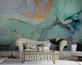 May include: A living room interior with a green and gold abstract art print on the wall. A sofa with pillows and a coffee table are in the foreground. A white armchair is in the background.