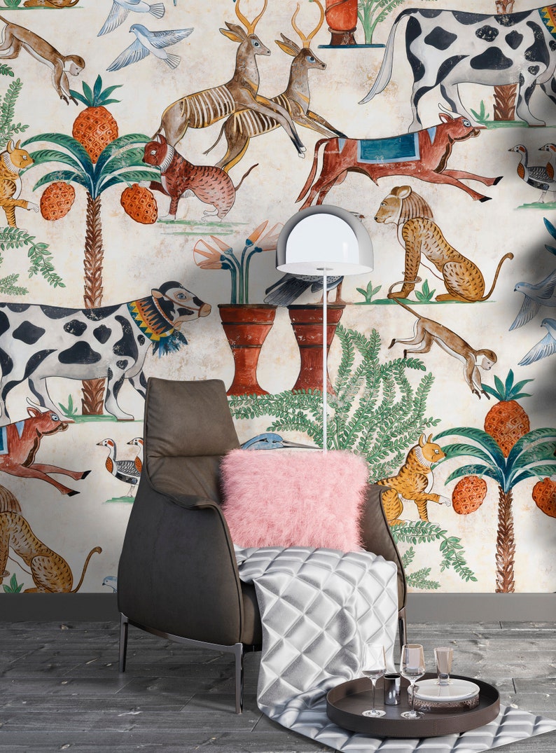 May include: A dark brown leather armchair with a pink faux fur pillow and a silver quilted throw blanket. The chair is positioned against a wall covered in wallpaper featuring a repeating pattern of various animals, palm trees, and pineapples.
