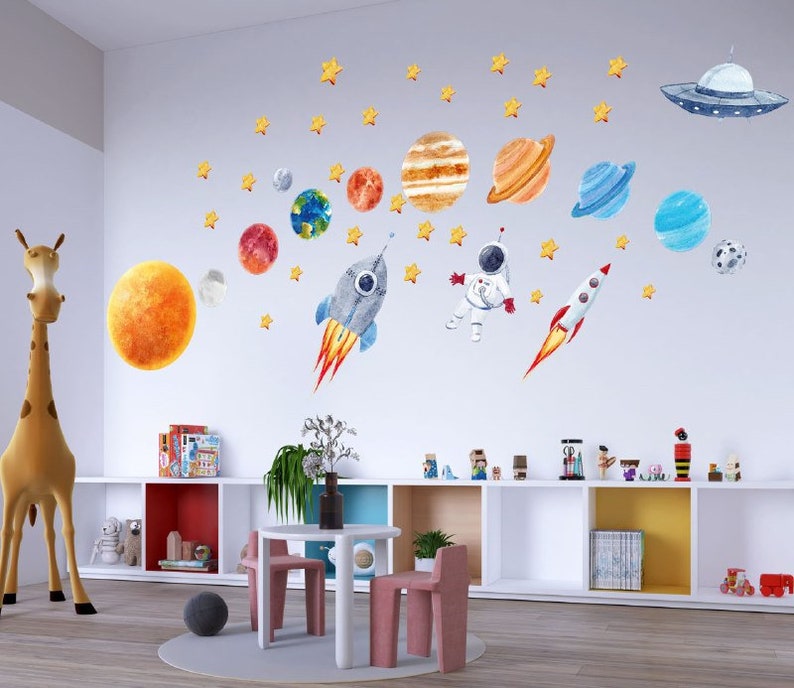 May include: A set of colorful space-themed wall decals featuring planets, stars, rockets, and an astronaut. The decals are perfect for a child's bedroom or playroom.
