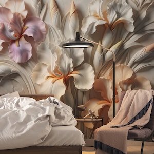 May include: A bedroom scene featuring a wall mural of large, sculpted, three-dimensional iris flowers in shades of soft pink, cream, and white. A black floor lamp with a gold arm stands next to a chair draped with a light pink and dark blue throw.