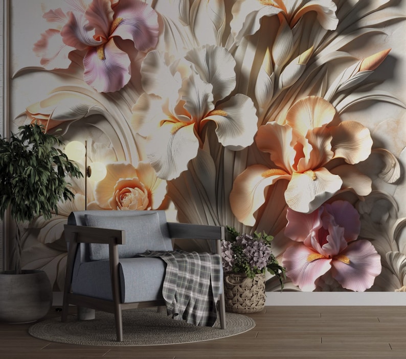 May include: A grey armchair with a plaid throw blanket sits before a wall mural featuring large, three-dimensional relief-style iris flowers in shades of soft pink, cream, and peach, accompanied by a potted plant and a small basket of purple flowers.