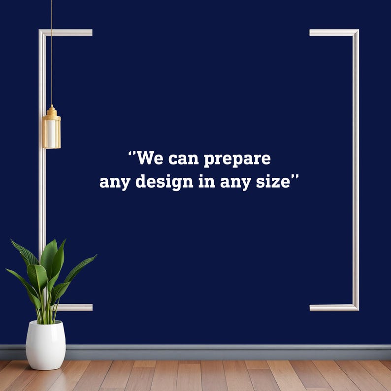 Op de afbeelding: Een marineblauwe muur met witte rechthoekige frames en de tekst "We can prepare any design in any size". Een goudkleurige lamp hangt aan het linkerbovenframe. Een potplant staat op een houten vloer.