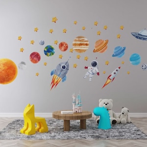 May include: A colorful space-themed wall decal set featuring planets, stars, a rocket, and an astronaut. The decals are perfect for a child's bedroom or playroom.