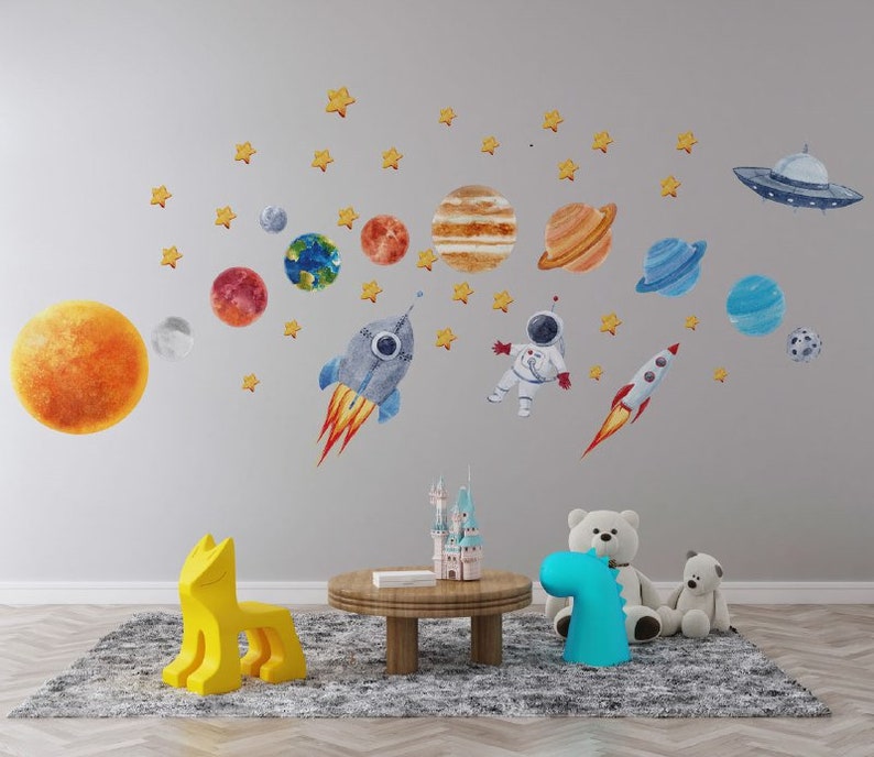 May include: A colorful space-themed wall decal set featuring planets, stars, a rocket, and an astronaut. The decals are perfect for a child's bedroom or playroom.