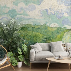 Puede incluir: Un mural de pared con una pintura al &oacute;leo texturizada de colinas verdes bajo un cielo azul claro y blanco. La escena se sit&uacute;a detr&aacute;s de un sof&aacute; gris claro, una mesa de centro de madera y dos plantas verdes en macetas de color blanco.