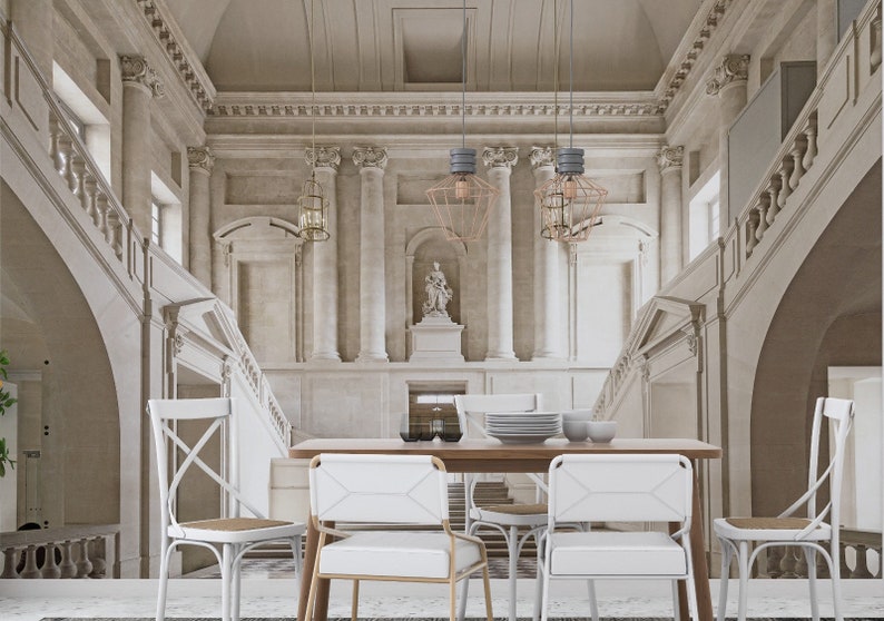 Op de afbeelding: Interieurontwerp van een eetkamer met een grandioze, klassieke architecturale achtergrond. De kamer heeft een houten tafel, witte stoelen en decoratieve hanglampen. De muren en het trappenhuis zijn in een neutraal kleurenpalet.