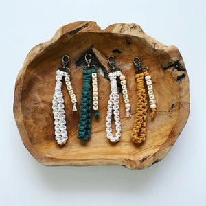 Peut inclure: Cinq porte-clés avec des noms différents épelés en perles de bois. Les porte-clés sont en cordon macramé blanc, vert et jaune.