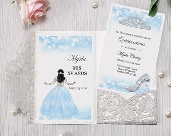 May include: A silver glitter and lace pocket folder with a blue and white invitation card inside. The invitation card features a cartoon illustration of a girl in a blue dress and the text "Myrla MIS XV AÑOS Mayo 23 2020". The invitation card also includes the text "Por favor únete a nosotros para un Quinceañera EN HONOR DE Myrla Chavez Sábado, Mayo 23 2020 Mayus Event Center 16026 SE start st. Portland OR 97233".