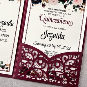 May include: Burgundy red laser cut invitation with a floral design and the text "MR. & MRS. WHITE CORDIALLY INVITE YOU TO CELEBRATE THE Quincea&ntilde;era OF THEIR DAUGHTER Jezaida Saturday, May 14th, 2022 Mass: at 2:00 pm PETER'S CHUR UR ADD"