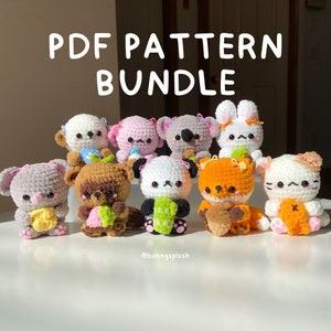 Puede incluir: Una colección de ocho peluches de animales amigurumi de crochet, incluyendo un panda, un zorro, un conejo, un koala, un gato, un oso y dos más. Los peluches llevan todos pequeños objetos, como una pieza de fruta o una taza de café. Los peluches están dispuestos en fila sobre una superficie blanca. El texto "PDF PATTERN BUNDLE" se muestra encima de los peluches. El texto "@bunnysplush" se muestra debajo de los peluches.