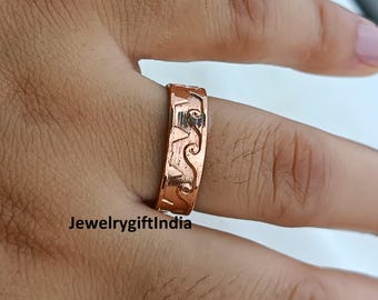 Peut inclure: Une bague de couleur cuivre avec un motif gravé de vagues et d'étoiles. La bague est portée au doigt. Le texte "JewelrygiftIndia" est visible en bas de l'image. Il s'agit d'un bijou.