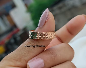 May include: A rose gold ring with a textured surface and a repeating geometric pattern. The ring is held between fingers, showcasing its design and craftsmanship. The text "Jewelrygiftindia" is visible.
