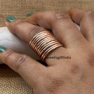 May include: A stack of 10 rose gold colored metal rings worn on a finger. The rings are thin and have a smooth, polished finish. The text "jewelrygiftindia" is visible on the bottom right of the image.