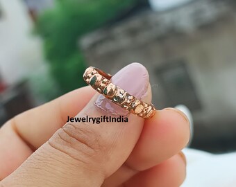 Op de afbeelding: Een koperkleurige ring met een textuur. De ring wordt tussen vingers gehouden. De tekst "jewelrygiftindia" is zichtbaar in de afbeelding.