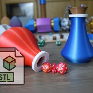 May include: A red and white 3D printed STL file for a dice rolling tower, with a blue 3D printed vase and red dice on a wooden table.
