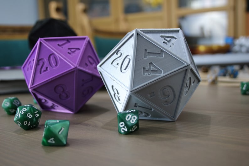 May include: Two 20-sided dice, one purple and one gray, with numbers 14, 20, 8, 16, 9, 1, 4, 6, 17, 20, 8, 9, 17, 14, 4, 1, 6, 10, 12, 3, and 20. There are also three smaller green dice with numbers 10, 20, 8, 16, 17, 7, 8, 20, 1, and 4.