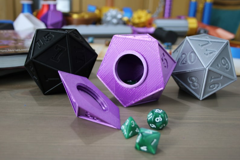 May include: A set of three purple and gray dice with a purple lidded box. The box is open and there are three green dice inside.