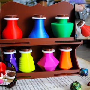 May include: A wooden shelf with seven colourful glass potion bottles. The bottles have brown lids and white rings around the necks. The shelf is on a table with dice and a book.