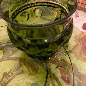 Puede incluir: Un juego de cuatro vasos para beber de vidrio verde con un dise&ntilde;o texturizado. Los vasos tienen una base redonda y un borde ancho.