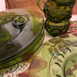 Puede incluir: Un juego de cuatro platos de vidrio verde con un dise&ntilde;o elevado alrededor del borde. Los platos est&aacute;n apilados uno encima del otro. Tambi&eacute;n hay tres tazas de vidrio verde con un dise&ntilde;o elevado alrededor del borde. Las tazas est&aacute;n apiladas una encima de la otra.