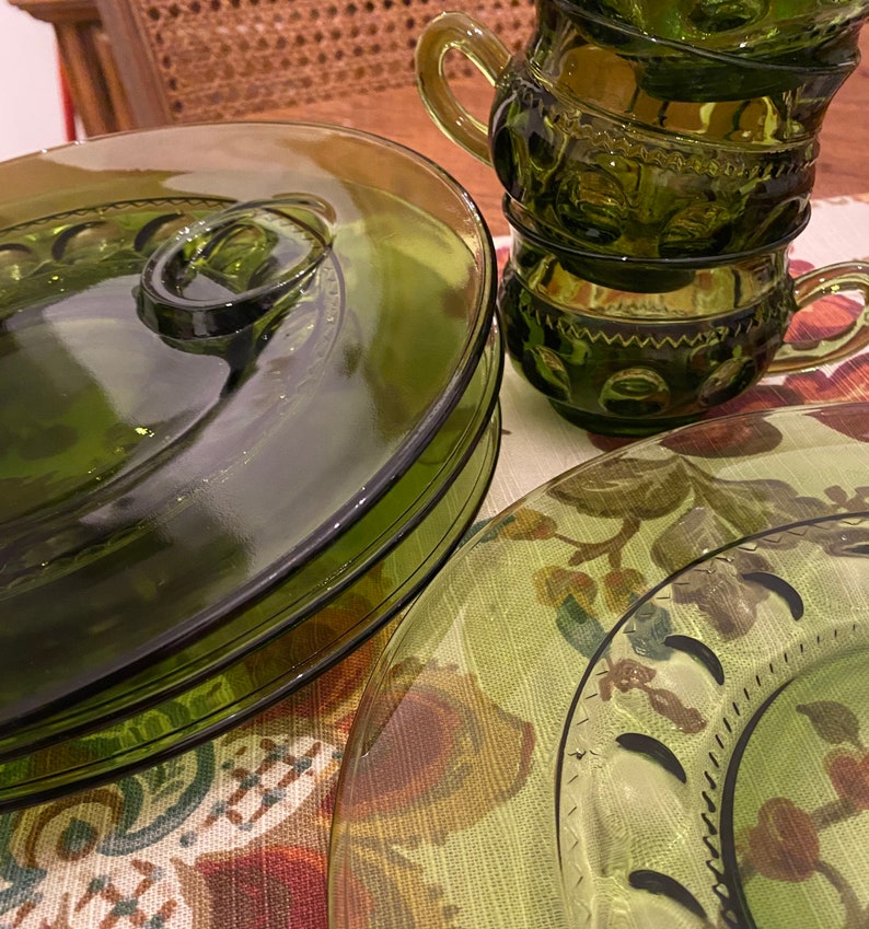 Puede incluir: Un juego de cuatro platos de vidrio verde con un dise&ntilde;o elevado alrededor del borde. Los platos est&aacute;n apilados uno encima del otro. Tambi&eacute;n hay tres tazas de vidrio verde con un dise&ntilde;o elevado alrededor del borde. Las tazas est&aacute;n apiladas una encima de la otra.