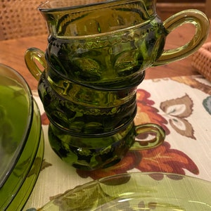 Puede incluir: Un juego de cuatro tazas de vidrio verde con un dise&ntilde;o texturizado. Las tazas est&aacute;n apiladas una encima de la otra.