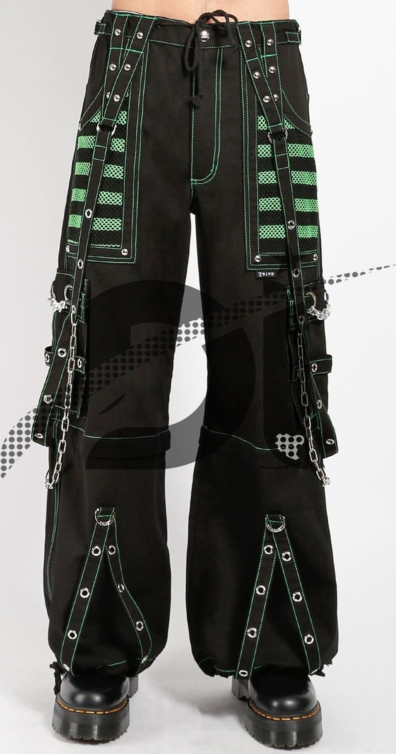 May include: Black cargo pants with green trim and silver hardware. The pants have multiple straps and buckles, as well as a chain detail on the side.