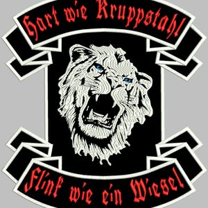 May include: Black and white embroidered patch with a white roaring lion in the center. The patch has two white banners with red text. The top banner reads "Hart wie Kruppstahl" and the bottom banner reads "Flink wie ein Wiesel".
