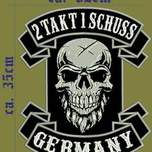 May include: Black and white embroidered patch with a skull and crossbones design. The patch has a white banner at the top that says "2 Takt I Schuss" and a white banner at the bottom that says "GERMANY". The patch is approximately 3.2 inches wide and 1.5 inches tall.