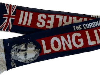 May include: A blue and red knitted scarf with white fringe. The scarf features a portrait of a person, the text "LONG LIVE" and "THE CORONATION OF CHARLES III".