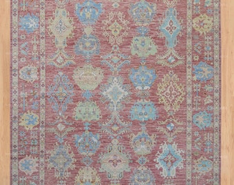 May include: A red rug with a traditional Persian design. The rug features intricate patterns in shades of blue, green, and beige. The rug has a border with a repeating pattern.