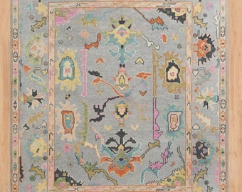 May include: A colorful rug with a geometric pattern in shades of blue, green, pink, orange, and black. The rug has a central medallion and a border with a repeating design.