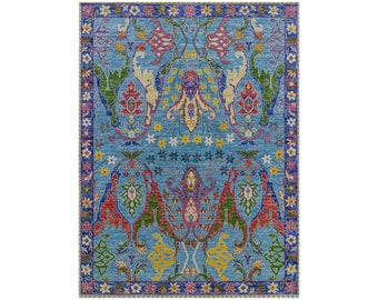 May include: A blue rug with a colorful floral pattern. The rug has a border of small flowers in various colors.