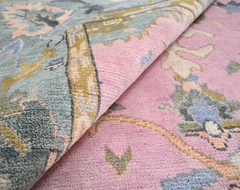 May include: Close-up of a pink and blue rug with a floral pattern. The rug is folded in half, showing the different colors and textures.