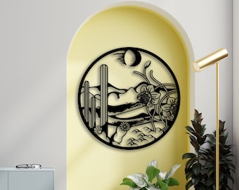 Può includere: Arte da parete in metallo nero che rappresenta un paesaggio desertico con cactus, fiori e una luna crescente. L'arte è circolare e ha uno stile rustico, sud-occidentale.