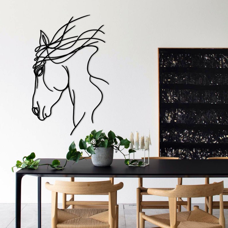 May include: Black and white line art of a horse's head on a white wall. The horse's mane is flowing in the wind. A black table with two wooden chairs is in the foreground.
