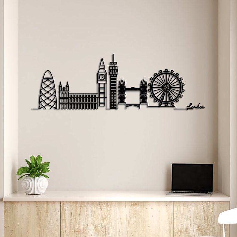 K&ouml;nnte beinhalten: Schwarze Metallsilhouette der Londoner Skyline, einschlie&szlig;lich London Eye, Big Ben und Shard. Das Wort "London" ist in Kursivschrift unter der Skyline geschrieben.
