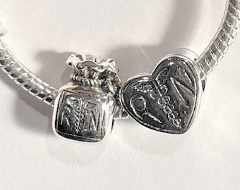 May include: A silver charm bracelet with two charms. One charm is a heart with the word "Love" inscribed on it. The other charm is a small bag with the letters "RN" on it.