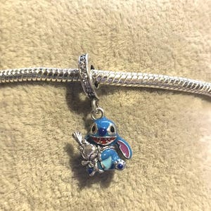 May include: A trio of cream-glazed ceramic mugs, each adorned with a hand-painted floral design. The flowers are rendered in blue, green, and yellow hues. The mugs have a rounded form and a practical handle, ideal for tea or coffee.