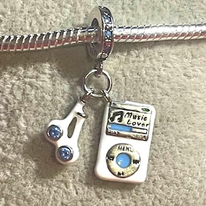 May include: A silver charm bracelet with a white iPod charm and a white treble clef charm. The iPod charm has the words "Music Lover" and a blue screen. The treble clef charm has two blue gems.
