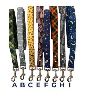 May include: Eight dog leads with diverse patterns, such as fish, trees, stars, and plaid. Each lead has a silver metal clasp and is labelled A to I. The leads are arranged vertically. The patterns include yellow spots and a navy blue starry design.