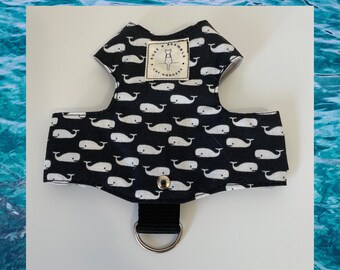 May include: Black cat harness with a white whale pattern. The harness has a black strap with a metal D-ring and a snap closure. The label reads "Rose & Bramble Cat Harnesses".