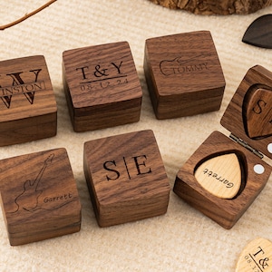 Può includere: Sei scatole di legno con disegni incisi. Le scatole sono in legno scuro e presentano una varietà di disegni, tra cui iniziali, date e strumenti musicali. Le scatole sono perfette per riporre piccoli oggetti, come gioielli, monete o plettri per chitarra.