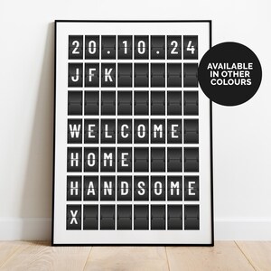 Könnte beinhalten: Schwarzweißes Schild im Flughafen-Stil mit dem Text "20.10.24 JFK WELCOME HOME HANDSOME X" in weißer Schrift. Das Schild ist in einem schwarzen Rahmen gerahmt.